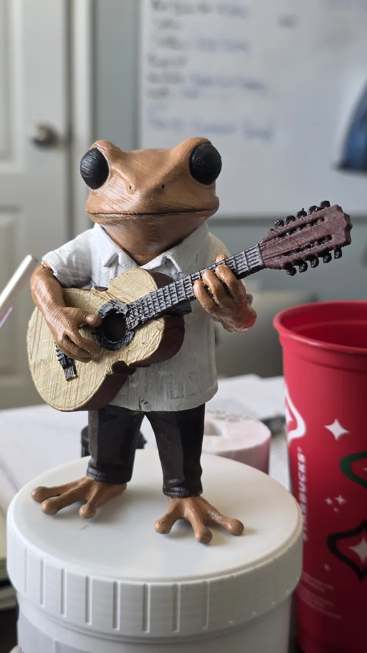 Small detailed sculptural mouse holding a guitar